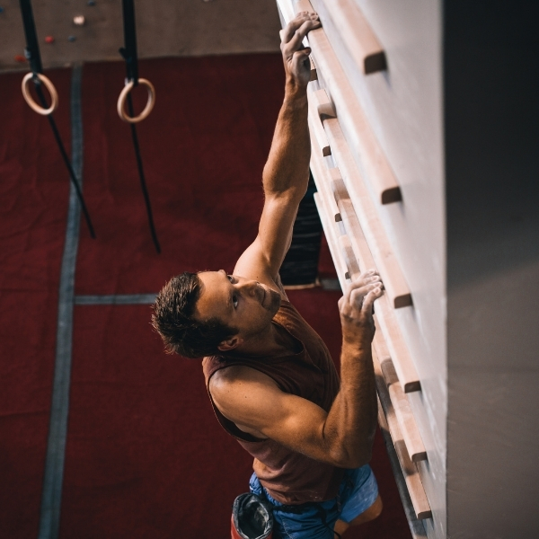 male climber on campus board in gym