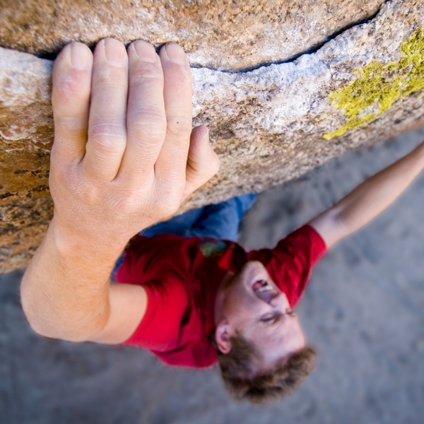 male climber hand on crimp hold on rockface
