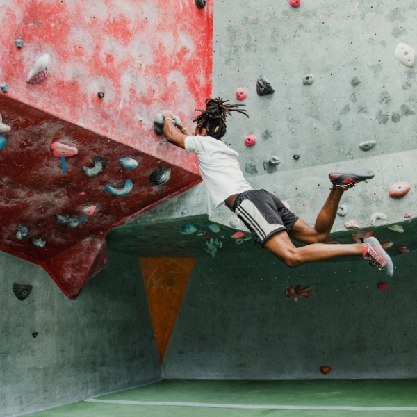 young girl hanging off indoor climbing wall