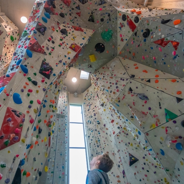 man looking up at indoor climbing walls