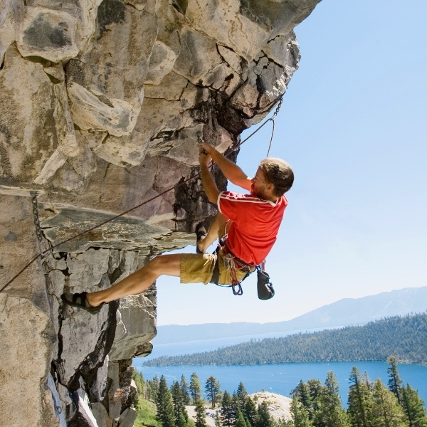 male climber with rope hanging from rock overhang