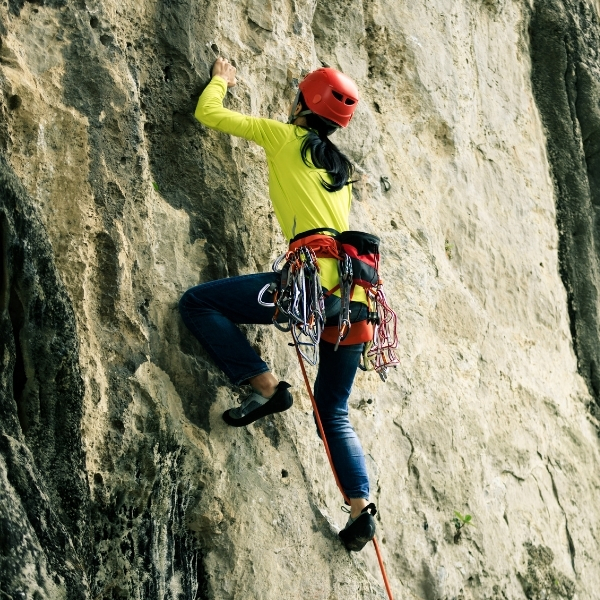 female rock climber rockface with helmet and equipment