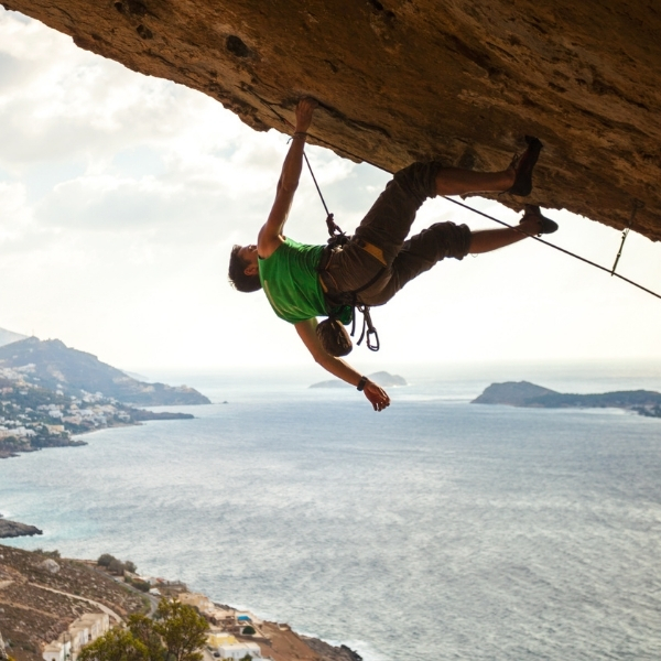 rockface overhang with male rock climber on ropes