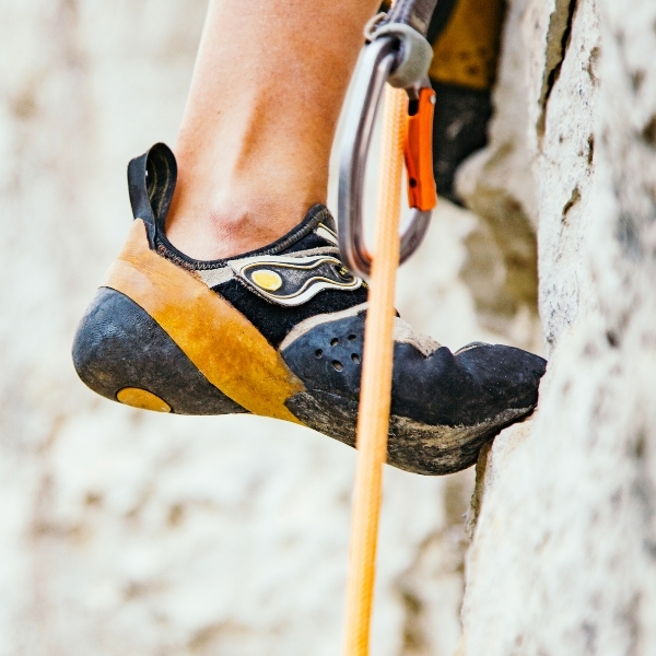 climbing shoes on rock with rope and carabiner